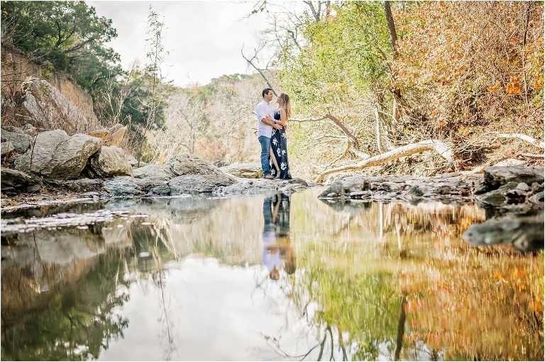 Engagement Photoshoot with Couple standing in Creek in Austin Texas Reflection Photograph Natural Light Photographer