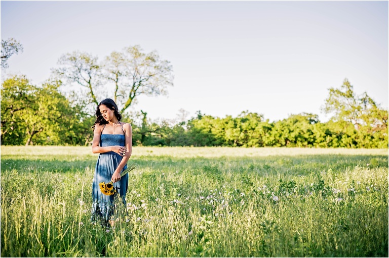 Senior Portrait Girl in field holding Sunflowers wearing blue dress Georgetown Texas Photographer