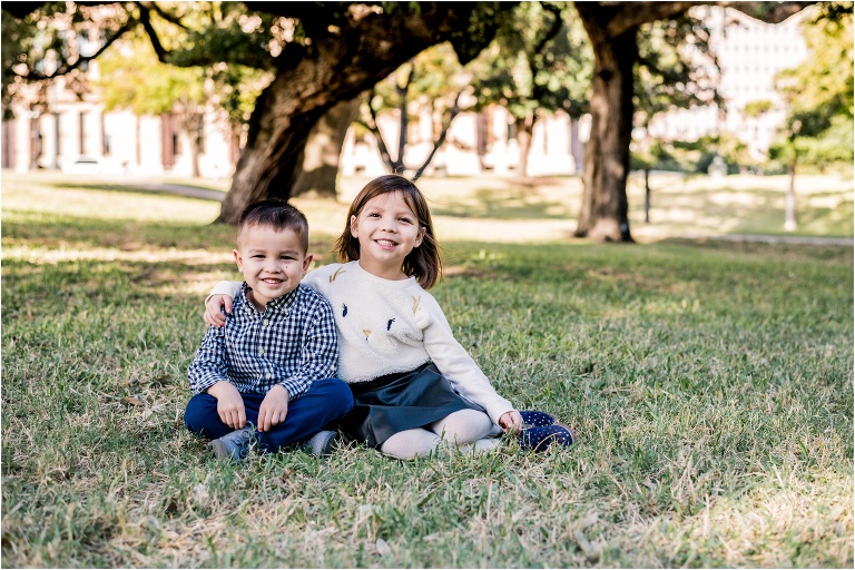 Brother and sister cuddling together in front of State Capital in Austin TX by natural light family portrait photographer