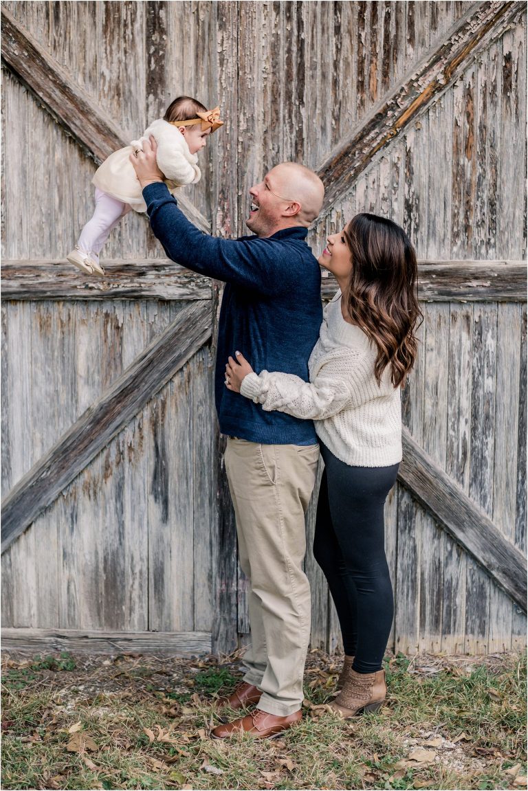 Beautiful family by white barn during Christmas photoshoot in Georgetown Texas by natural light portrait photographer