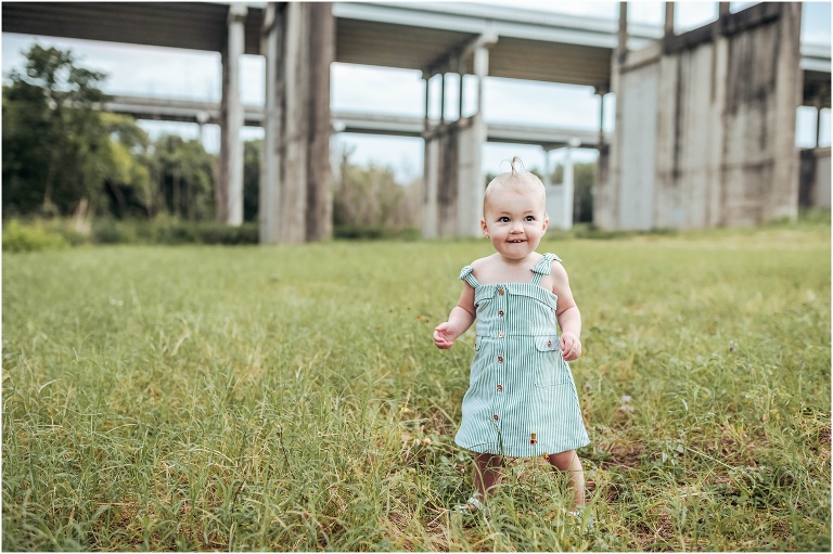 little girl in field wearing striped dress during first birthday photoshoot in natural light children portrait photographer in Georgetown Texas